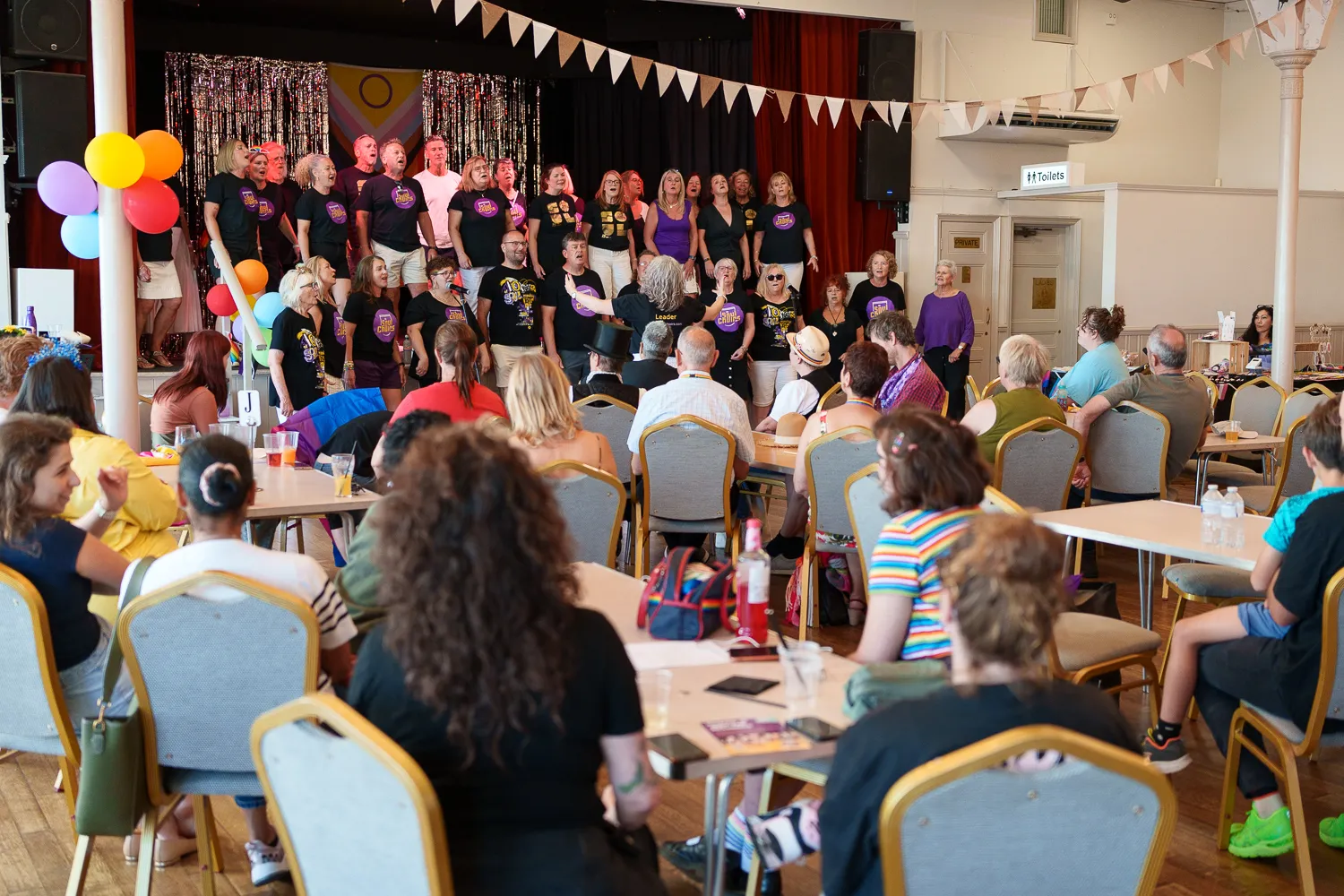 A choir performing beneath bunting in front of a seated audience