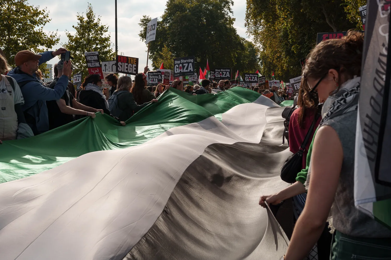 Demonstrators holding the edges of a large Palestinian flag