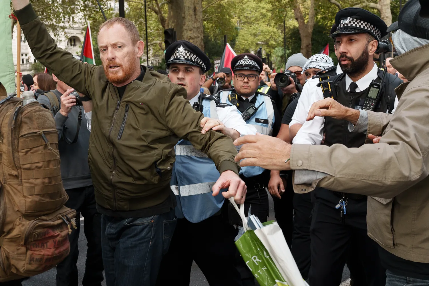 Police officers removing a man from a crowd on Embankment