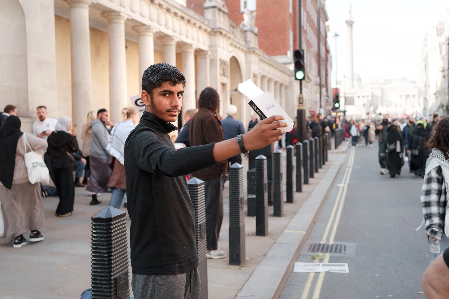 A person holding up a quran beside a line of street bollards