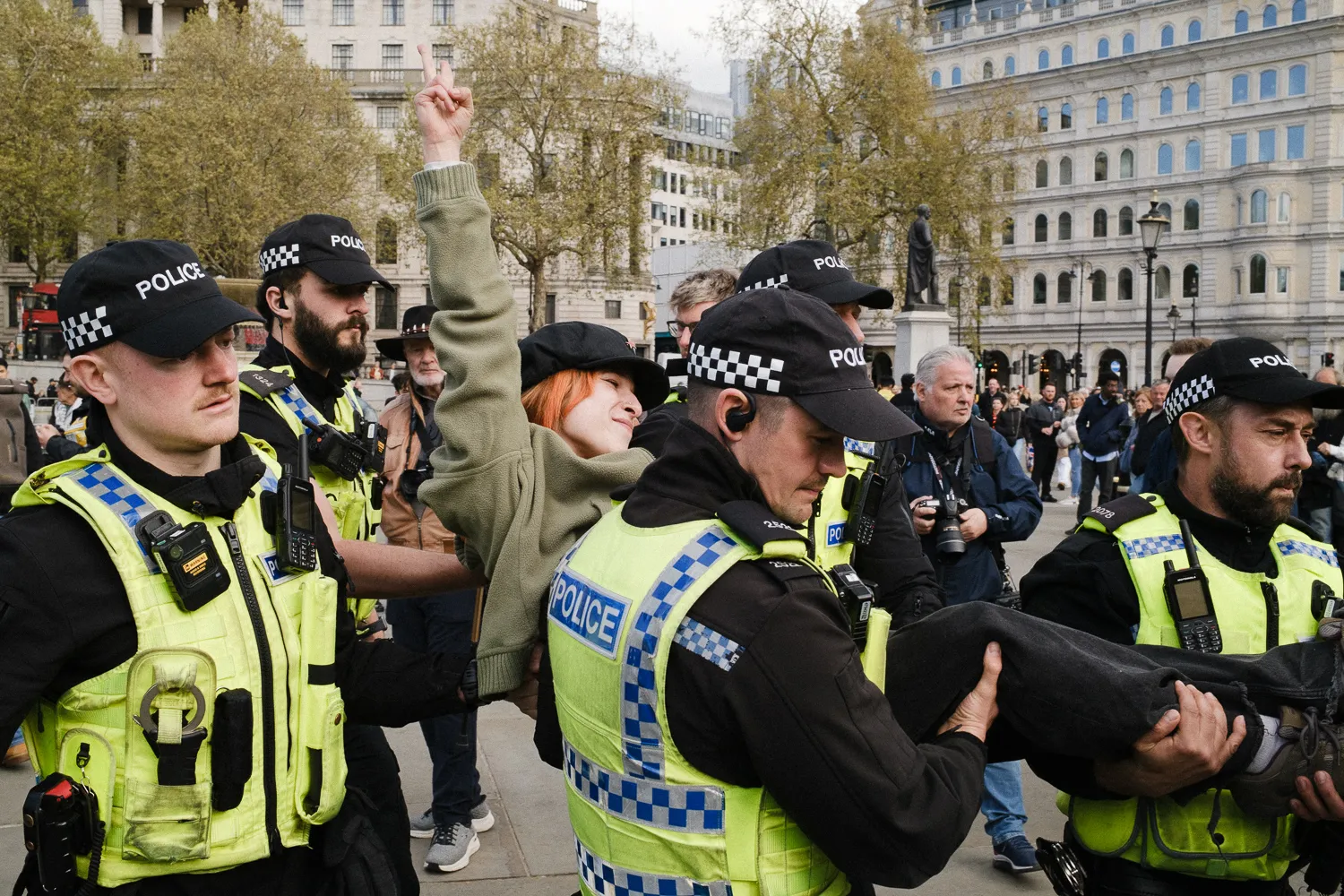 A woman with a raised fist carried by police officers
