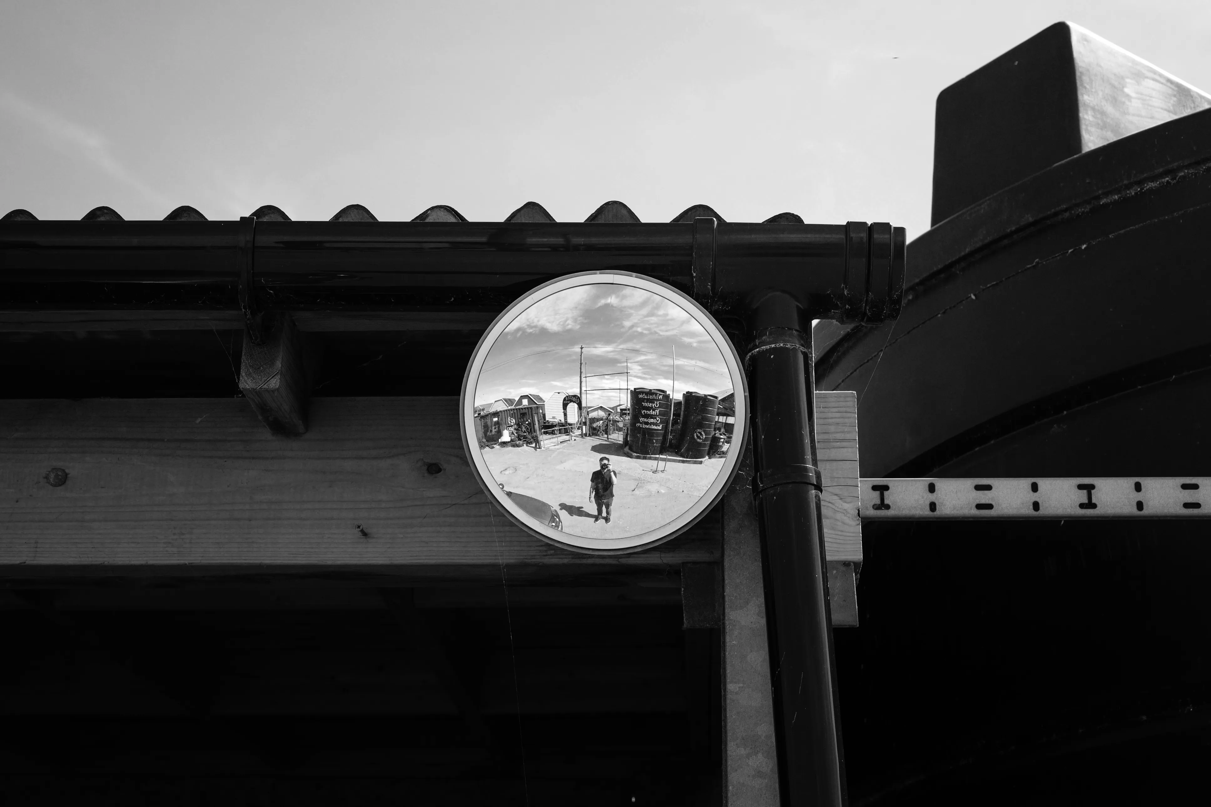 Nick Harris reflected in a convex mirror beside beach huts