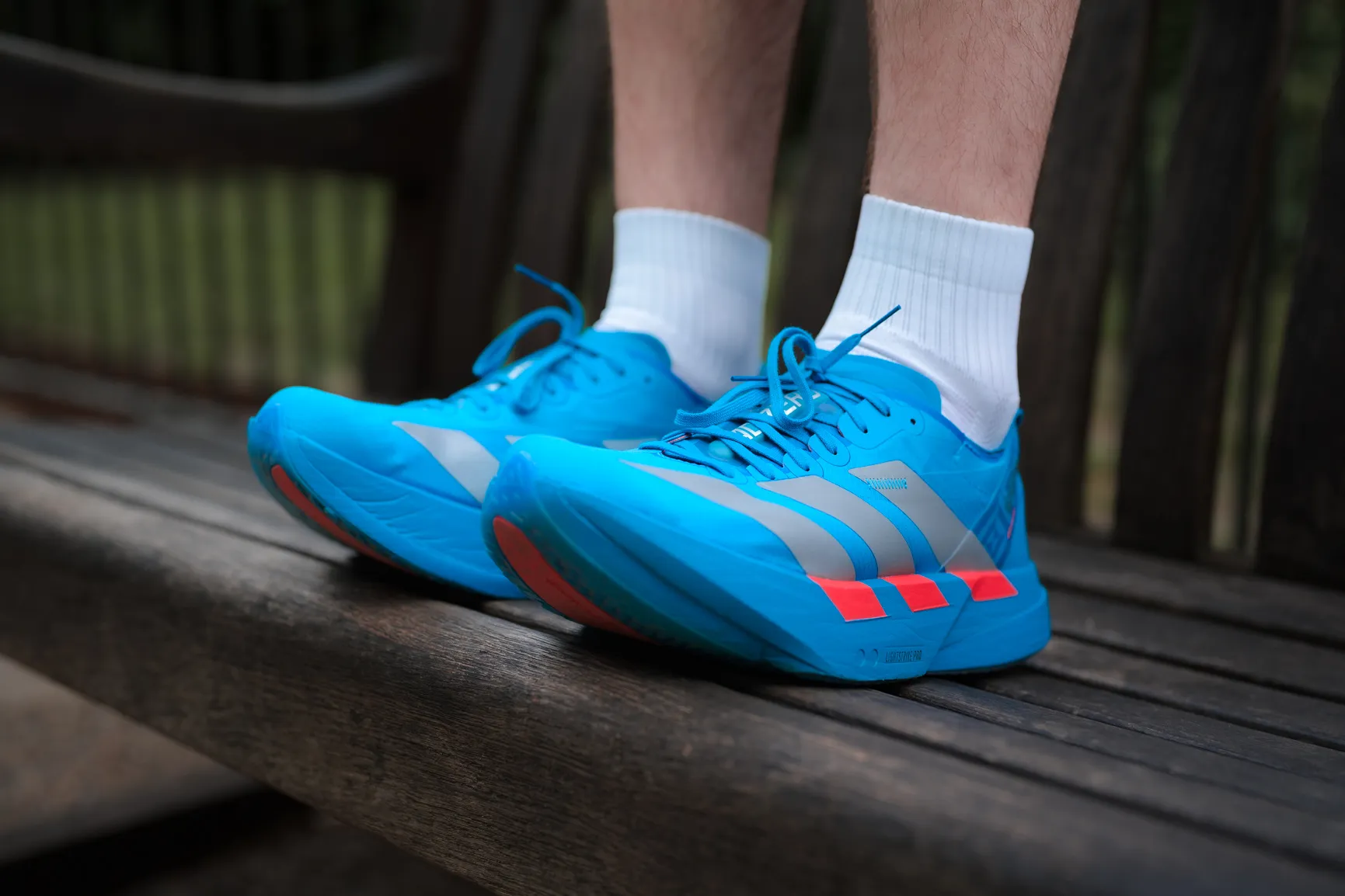 Bright blue adidas running shoes worn on a wooden bench