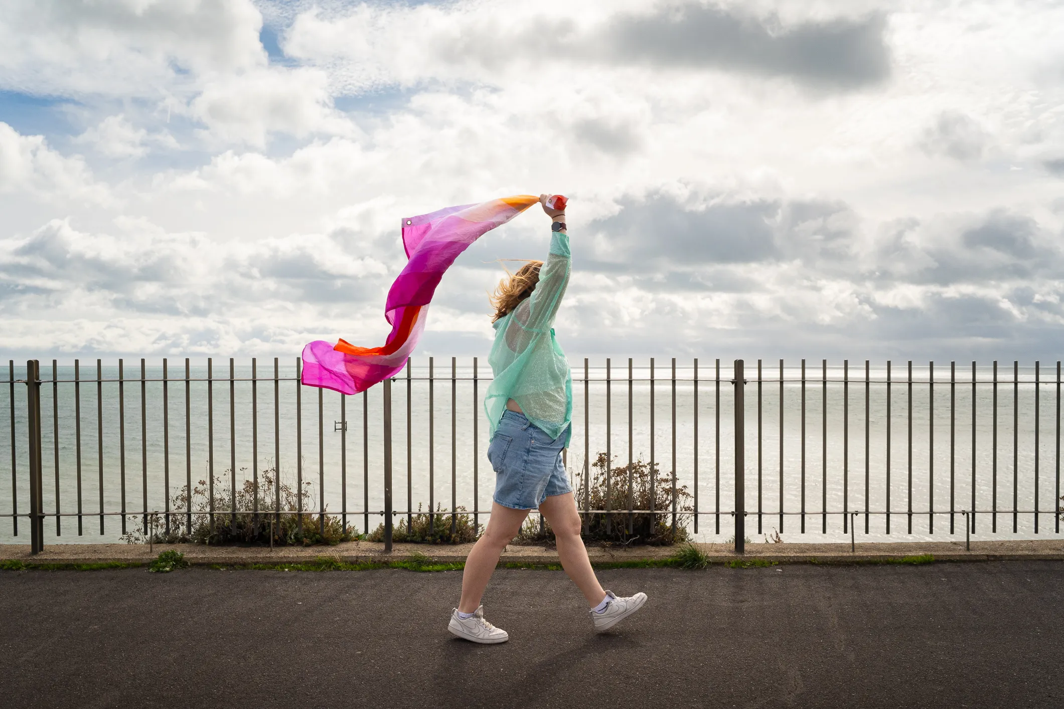 Little Rouge walking holding a flag at the head of the Ramsgate Pride parade